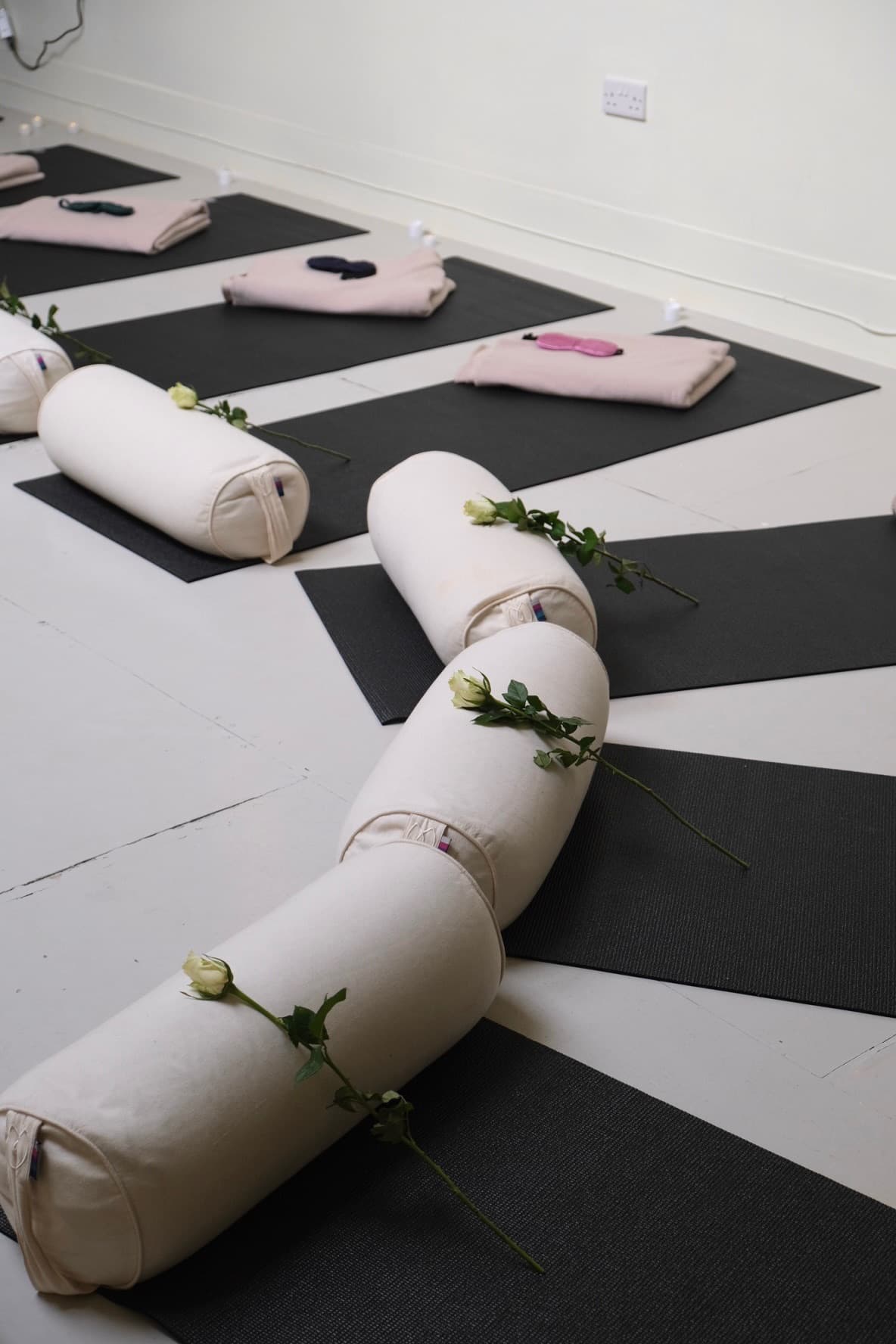 Yoga mats dressed with bolsters and white roses
